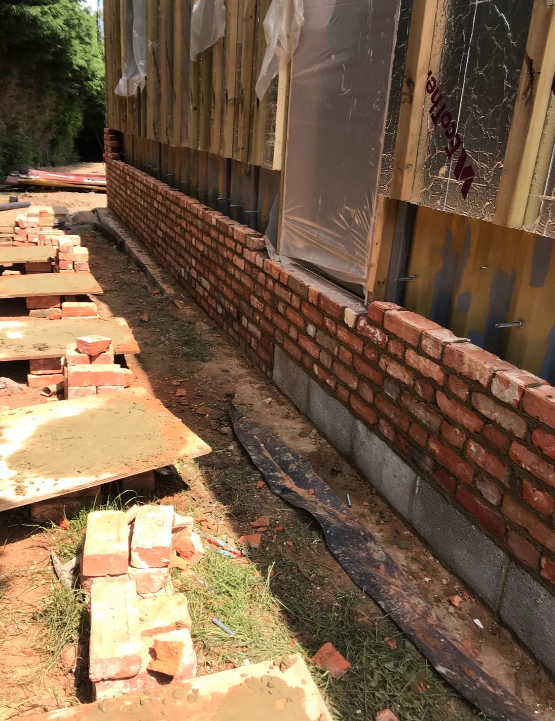 Early courses of reclaimed brick skin on new build